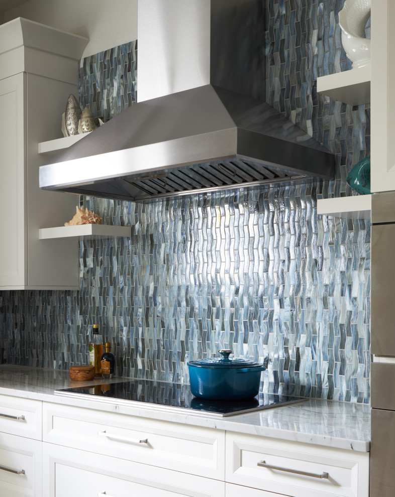 Example of a large beach style l-shaped porcelain tile and gray floor kitchen design in Other with a farmhouse sink, recessed-panel cabinets, white cabinets, quartzite countertops, multicolored backsplash, glass tile backsplash, stainless steel appliances, an island and blue countertops