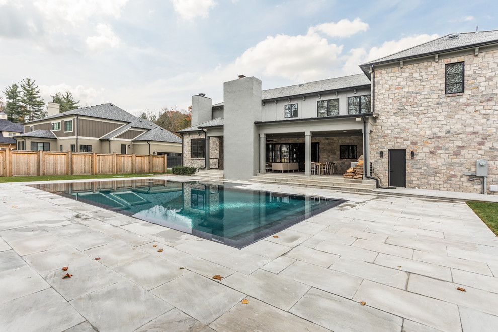 Large backyard concrete paver and custom-shaped infinity pool photo in Indianapolis