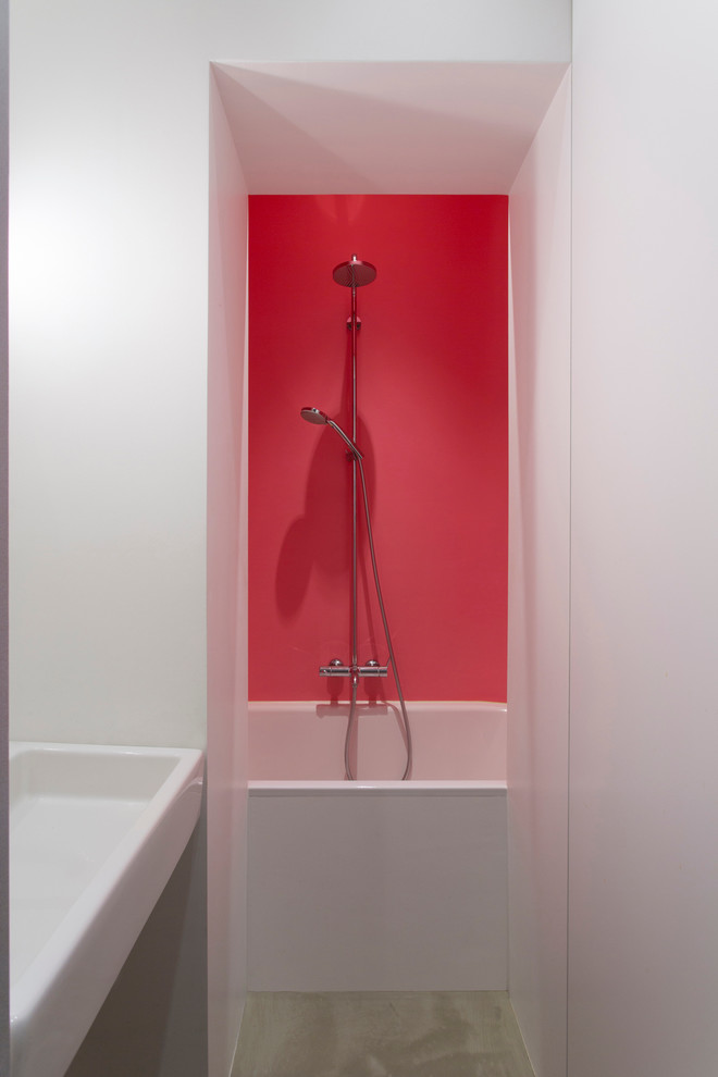 Imagen de cuarto de baño contemporáneo pequeño con bañera encastrada, combinación de ducha y bañera, paredes rojas, suelo de cemento y lavabo suspendido