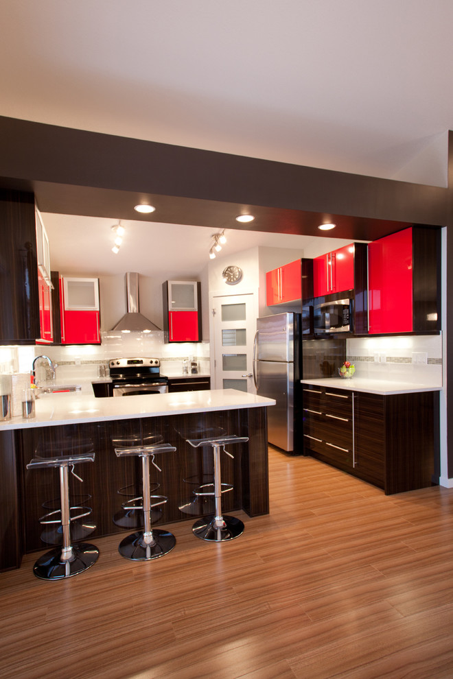 Photo of a contemporary u-shaped kitchen in Calgary with flat-panel cabinets, red cabinets, white splashback and stainless steel appliances.