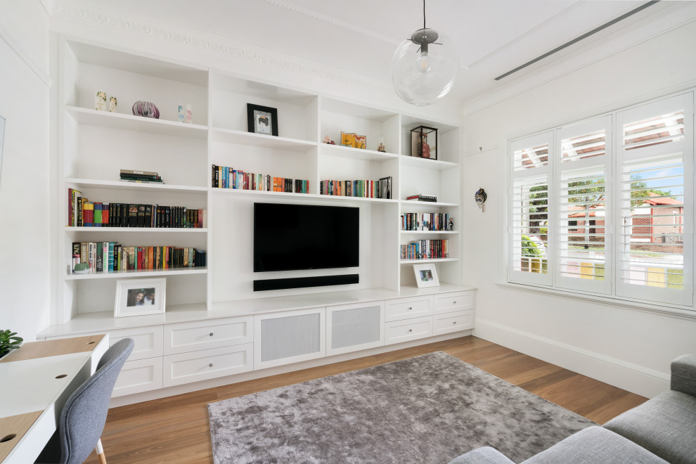 This is an example of a mid-sized transitional enclosed living room in Sydney with a library, medium hardwood floors and a built-in media wall.