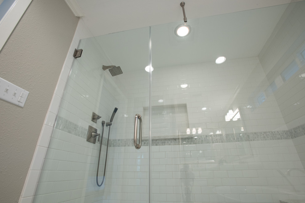 Modern inredning av ett badrum, med skåp i shakerstil, vita skåp, ett fristående badkar, vit kakel, marmorkakel, beige väggar, marmorgolv och marmorbänkskiva