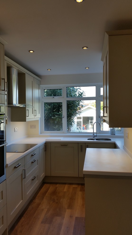 Photo of a mid-sized transitional u-shaped eat-in kitchen in Kent with shaker cabinets and white splashback.