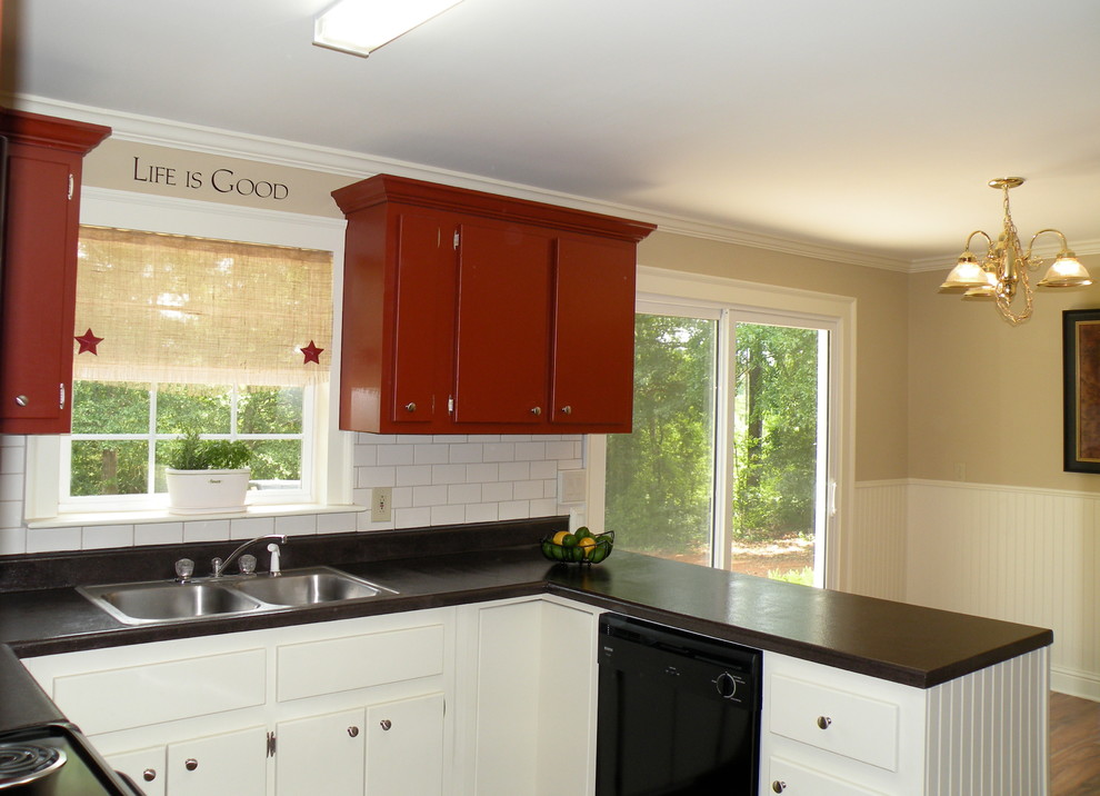 This is an example of a mid-sized traditional u-shaped eat-in kitchen in Atlanta with a drop-in sink, flat-panel cabinets, red cabinets, laminate benchtops, white splashback, ceramic splashback, black appliances, medium hardwood floors and no island.