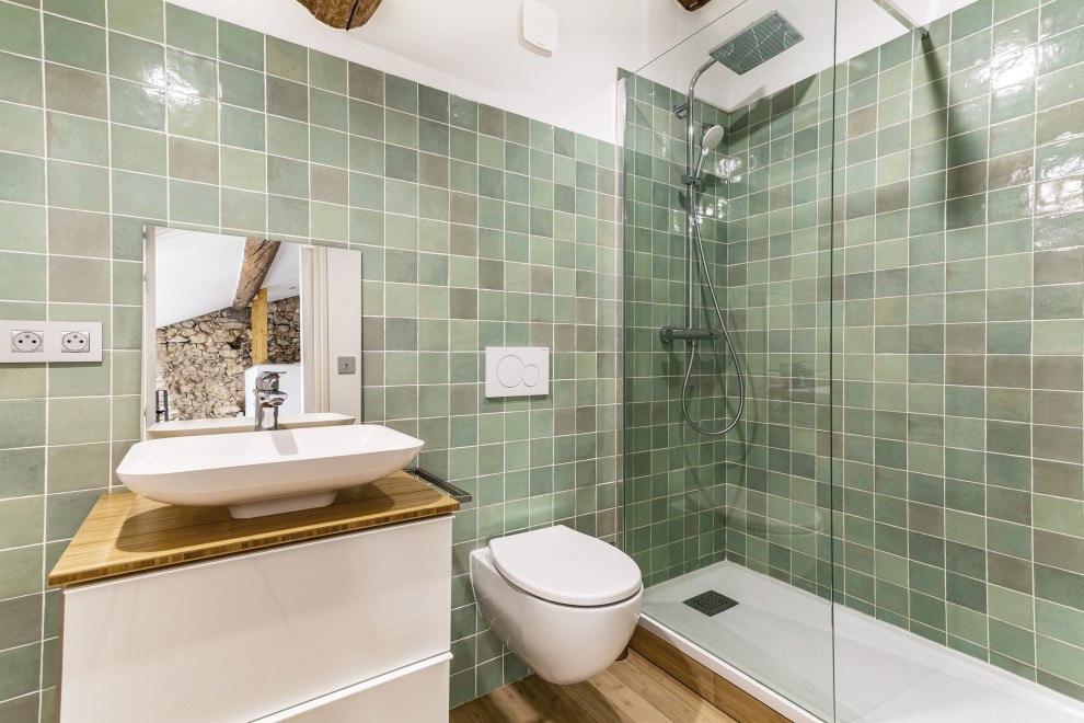 Modelo de cuarto de baño contemporáneo pequeño con ducha abierta, sanitario de pared, baldosas y/o azulejos verdes, suelo de bambú, lavabo encastrado, encimeras blancas y vigas vistas