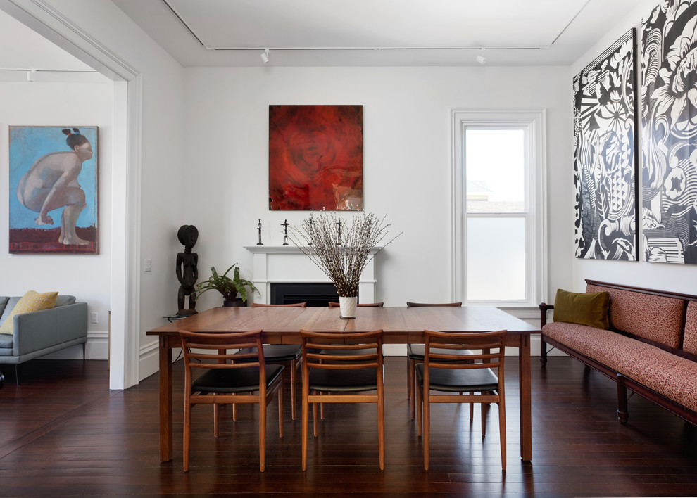 Mid-sized contemporary separate dining room in San Francisco with white walls, dark hardwood floors, a standard fireplace, a wood fireplace surround and brown floor.