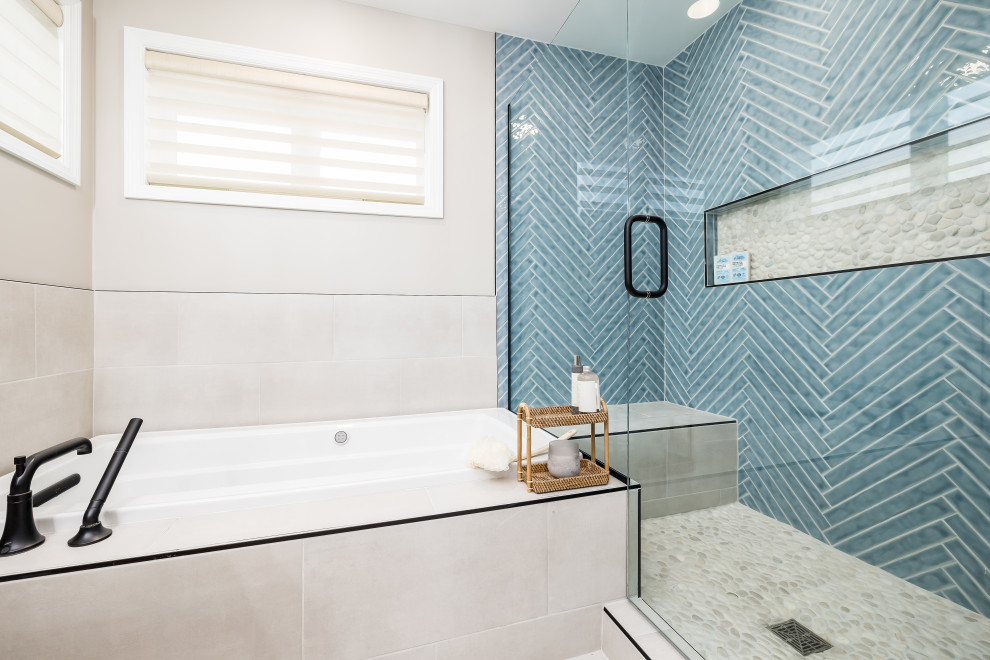 Design ideas for a large coastal ensuite bathroom in Minneapolis with flat-panel cabinets, light wood cabinets, a built-in bath, an alcove shower, a one-piece toilet, blue tiles, ceramic tiles, beige walls, porcelain flooring, a submerged sink, marble worktops, beige floors, a hinged door, white worktops, a laundry area, double sinks, a freestanding vanity unit and wallpapered walls.