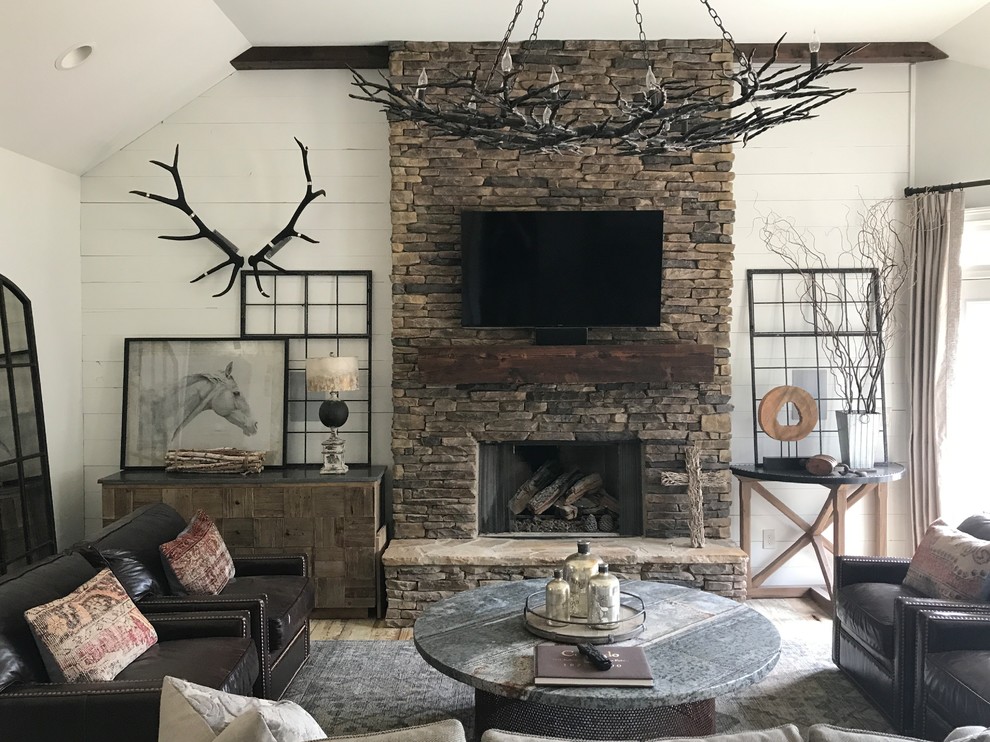 Inspiration for a large country enclosed family room in Atlanta with white walls, medium hardwood floors, a standard fireplace, a stone fireplace surround, a wall-mounted tv and brown floor.