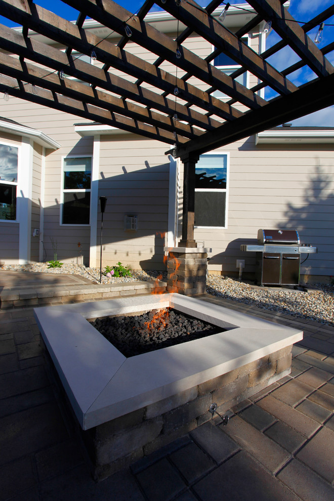 This is an example of a small traditional backyard patio in Indianapolis with a fire feature, concrete pavers and a pergola.