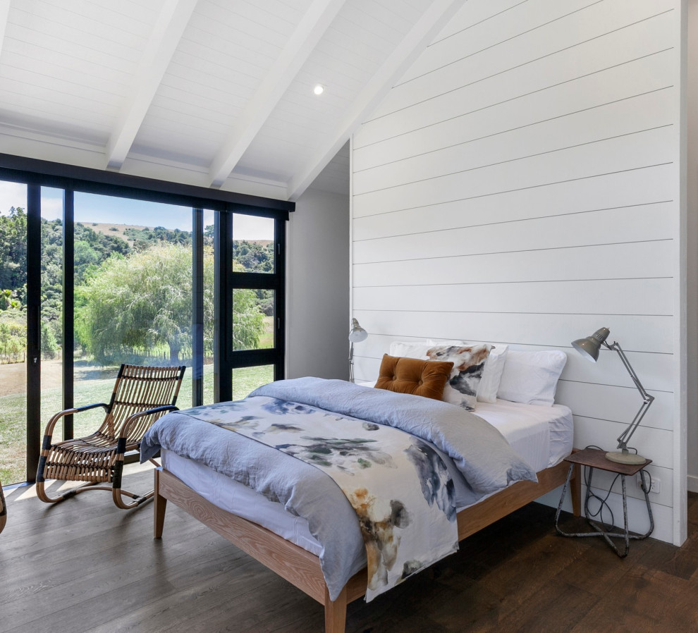 Country master bedroom in Other with white walls, dark hardwood floors, brown floor, vaulted and planked wall panelling.