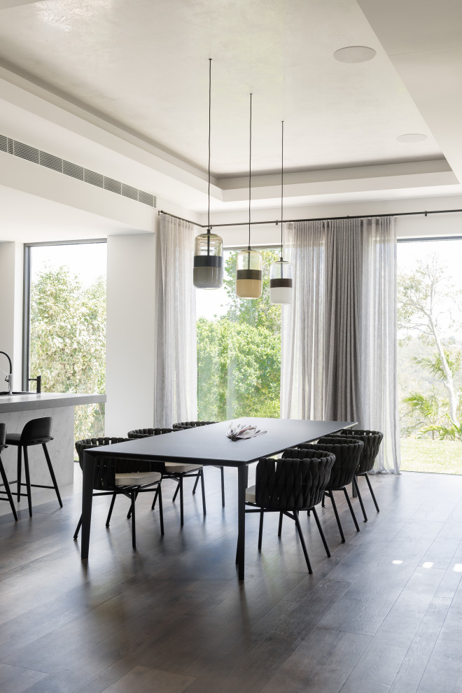 Modern dining room in Sydney with white walls, dark hardwood floors and brown floor.