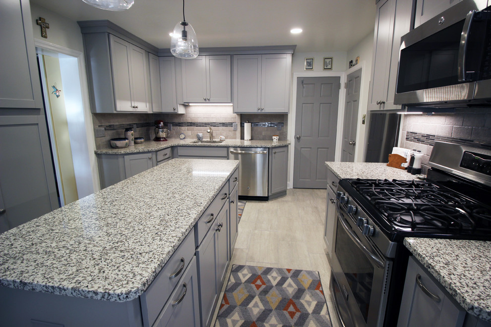 This is an example of a mid-sized traditional u-shaped eat-in kitchen in Wilmington with an undermount sink, shaker cabinets, grey cabinets, granite benchtops, beige splashback, stone tile splashback, stainless steel appliances, ceramic floors, with island and grey floor.