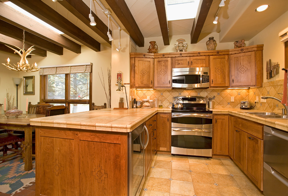 This is an example of a small u-shaped eat-in kitchen in Albuquerque with an undermount sink, flat-panel cabinets, light wood cabinets, tile benchtops, beige splashback, ceramic splashback, stainless steel appliances, ceramic floors and no island.