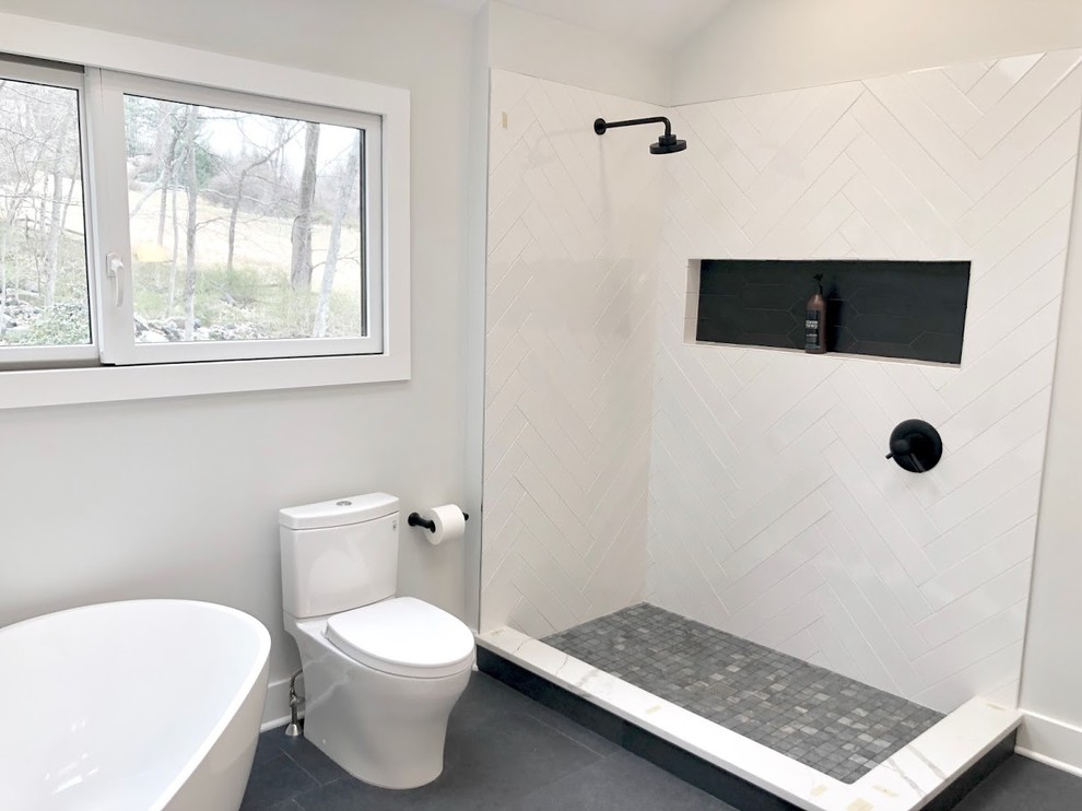 Photo of a large scandinavian master bathroom in New York with flat-panel cabinets, light wood cabinets, a freestanding tub, a corner shower, a two-piece toilet, white tile, porcelain tile, white walls, porcelain floors, an undermount sink, quartzite benchtops, black floor, a hinged shower door and white benchtops.