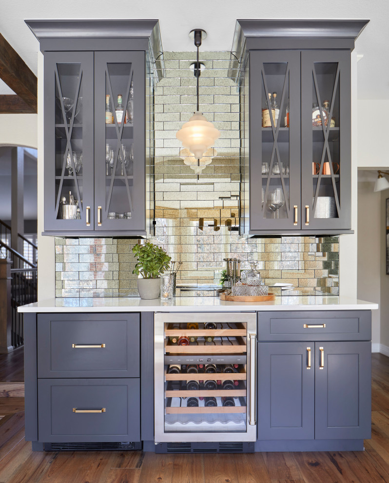 This is an example of a mid-sized modern single-wall home bar in Denver with shaker cabinets, blue cabinets, quartzite benchtops, grey splashback, mirror splashback, medium hardwood floors, brown floor and white benchtop.