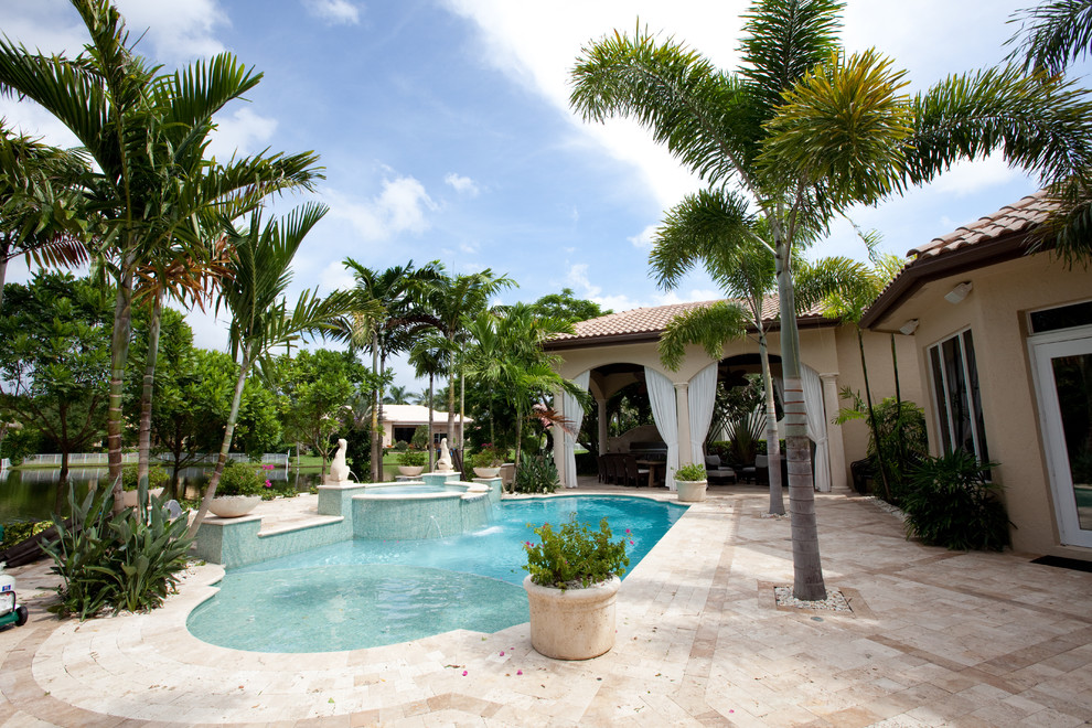 Photo of a mid-sized tropical backyard custom-shaped lap pool in Miami with a hot tub and tile.