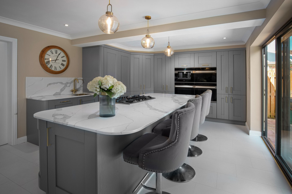 This is an example of a large contemporary l-shaped kitchen in Other with an integrated sink, shaker cabinets, grey cabinets, white splashback, engineered quartz splashback, black appliances, plywood floors, with island, white floor and white benchtop.