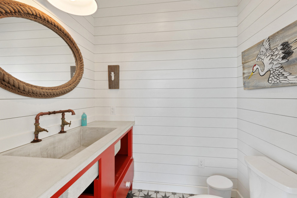 Foto på ett litet maritimt grå badrum med dusch, med öppna hyllor, röda skåp, en toalettstol med hel cisternkåpa, vita väggar, klinkergolv i keramik, ett avlångt handfat och bänkskiva i betong