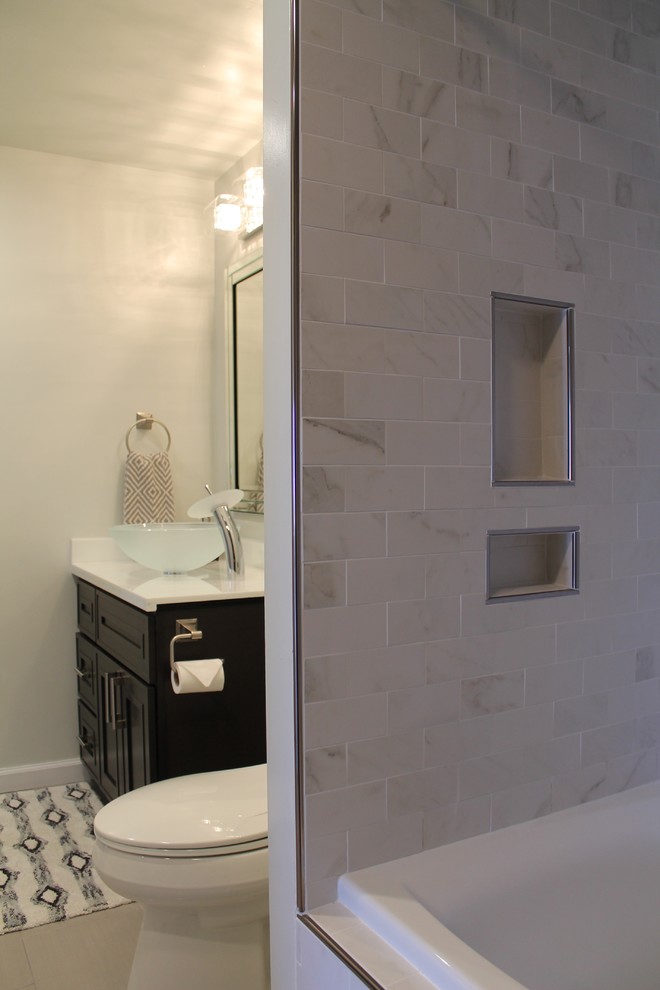 Photo of a mid-sized transitional master bathroom in San Francisco with dark wood cabinets, beige tile, stone tile, white walls, ceramic floors, a vessel sink, beaded inset cabinets, an alcove tub, a shower/bathtub combo, a two-piece toilet, engineered quartz benchtops and grey floor.