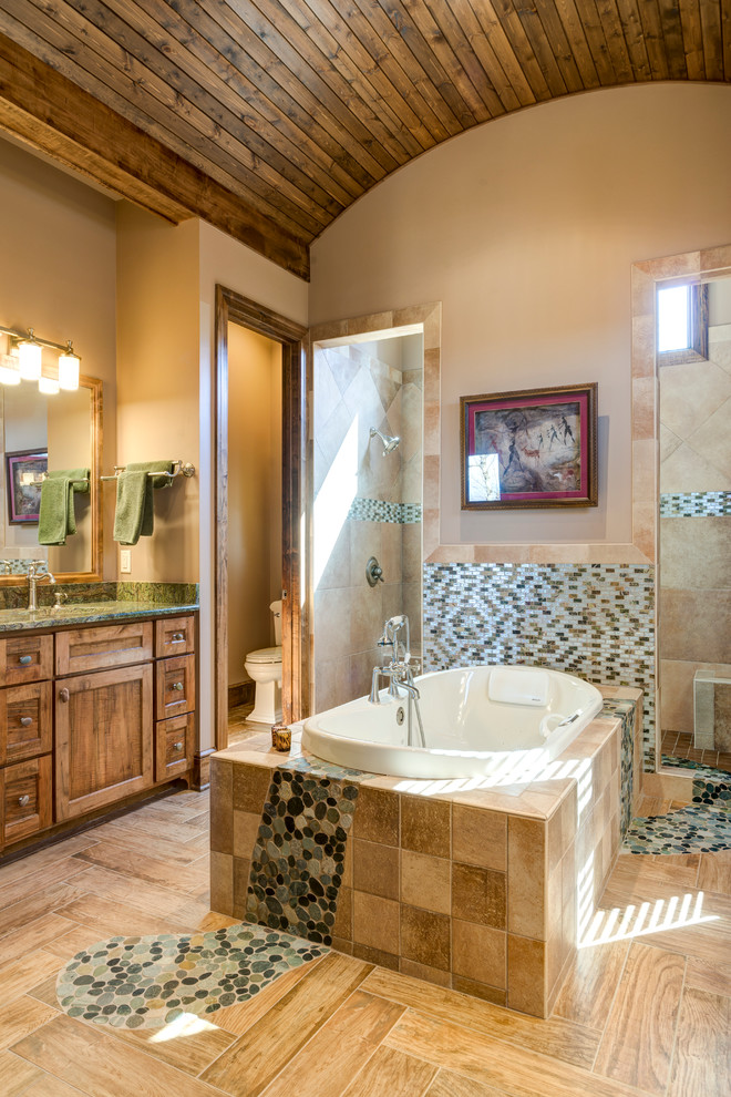 This is an example of a country bathroom in Other with shaker cabinets, medium wood cabinets, a drop-in tub, beige tile and beige walls.