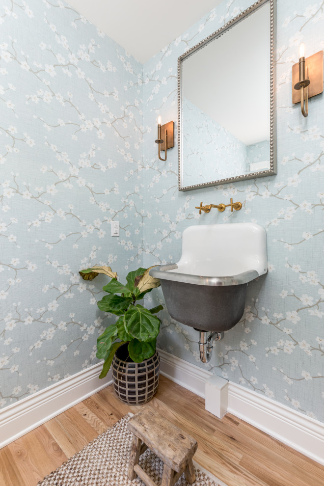 Cette image montre un WC et toilettes avec WC à poser, un mur multicolore, parquet clair, un lavabo suspendu, un sol marron et du papier peint.