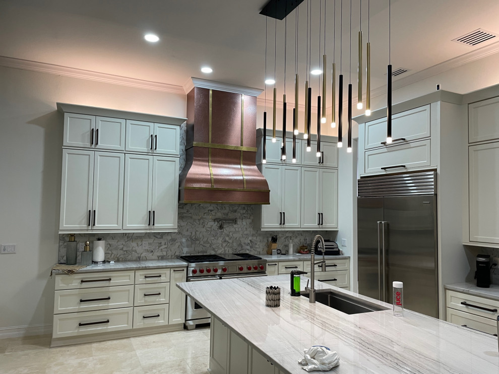 Large contemporary kitchen pantry in Orange County with a drop-in sink, shaker cabinets, white cabinets, quartzite benchtops, white splashback, marble splashback, stainless steel appliances, travertine floors, with island, multi-coloured benchtop and coffered.