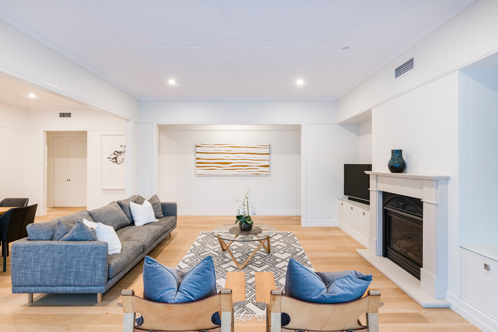 Mid-sized traditional living room in Brisbane with white walls, light hardwood floors, a standard fireplace, a wood fireplace surround and a freestanding tv.