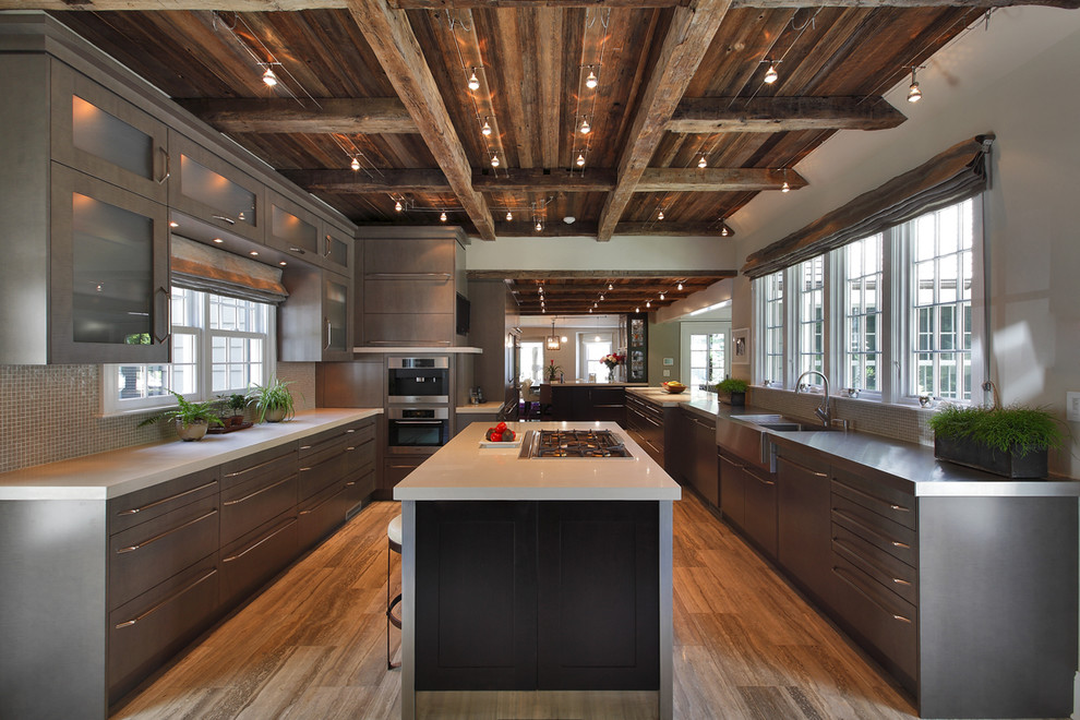 This is an example of a large country u-shaped separate kitchen in New York with stainless steel appliances, flat-panel cabinets, an integrated sink, medium wood cabinets, concrete benchtops, grey splashback, ceramic splashback, travertine floors and with island.