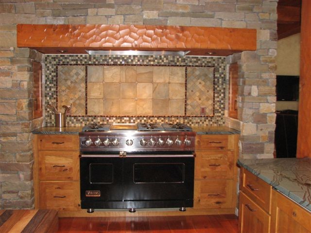Inspiration for a large rustic medium tone wood floor kitchen remodel with flat-panel cabinets, medium tone wood cabinets, marble countertops, multicolored backsplash, stone tile backsplash and black appliances
