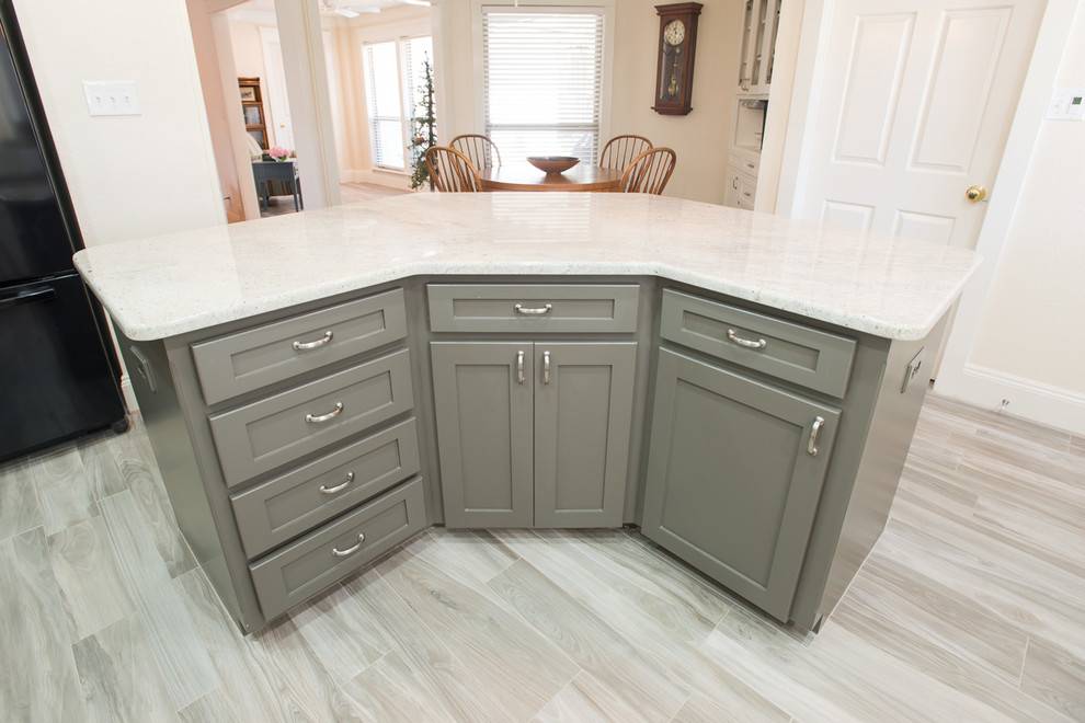 Small transitional l-shaped ceramic tile eat-in kitchen photo in Dallas with a drop-in sink, recessed-panel cabinets, white cabinets, white backsplash, subway tile backsplash, black appliances and an island