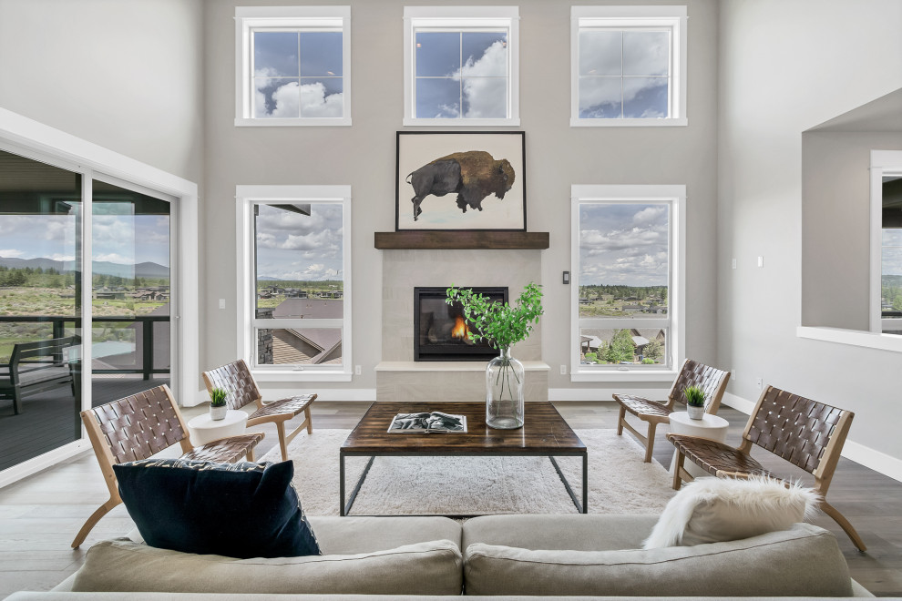 Inspiration for a large modern open concept living room in Portland with grey walls, medium hardwood floors, a standard fireplace, a stone fireplace surround and vaulted.