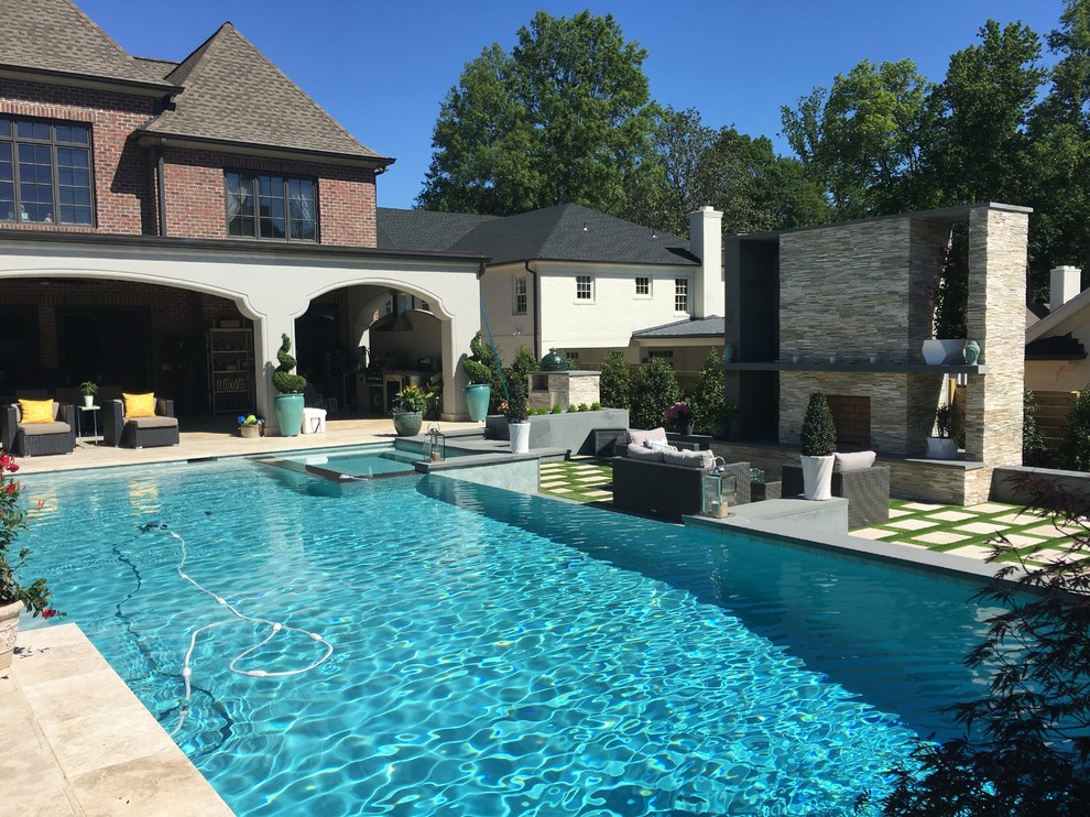 This is an example of a large contemporary backyard rectangular infinity pool in Charlotte with a hot tub and brick pavers.