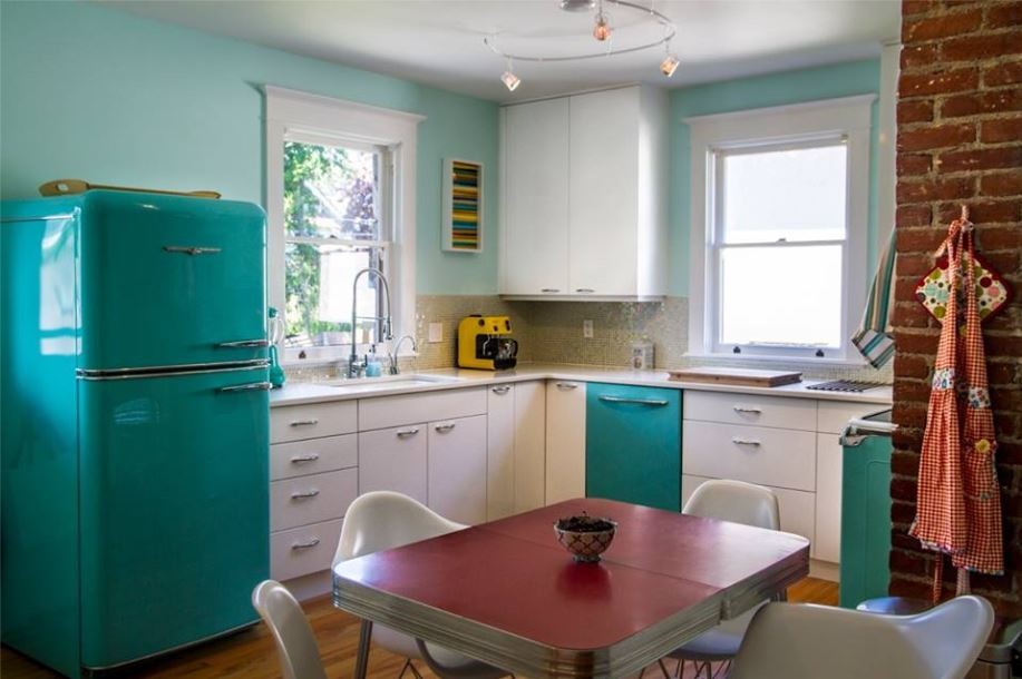 Inspiration for a midcentury eat-in kitchen in Vancouver with an undermount sink, flat-panel cabinets, white cabinets, solid surface benchtops, beige splashback, metal splashback, coloured appliances, light hardwood floors and no island.