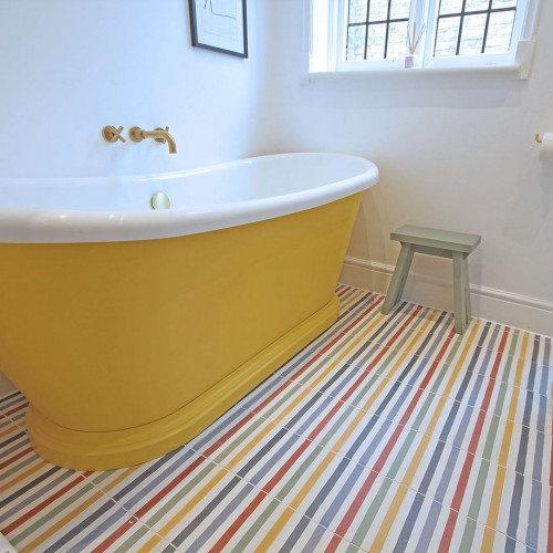 Yellow freestanding bath tub with rainbow floor tiles
