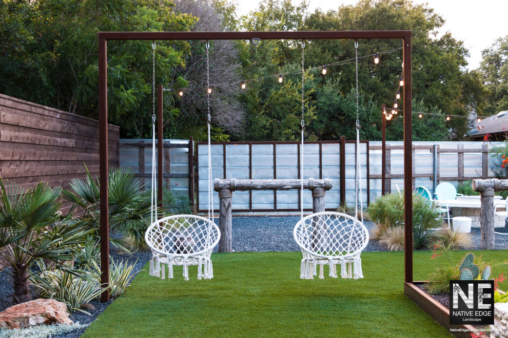 Photo of a mid-sized backyard full sun xeriscape for summer in Austin with with outdoor playset, gravel and a metal fence.
