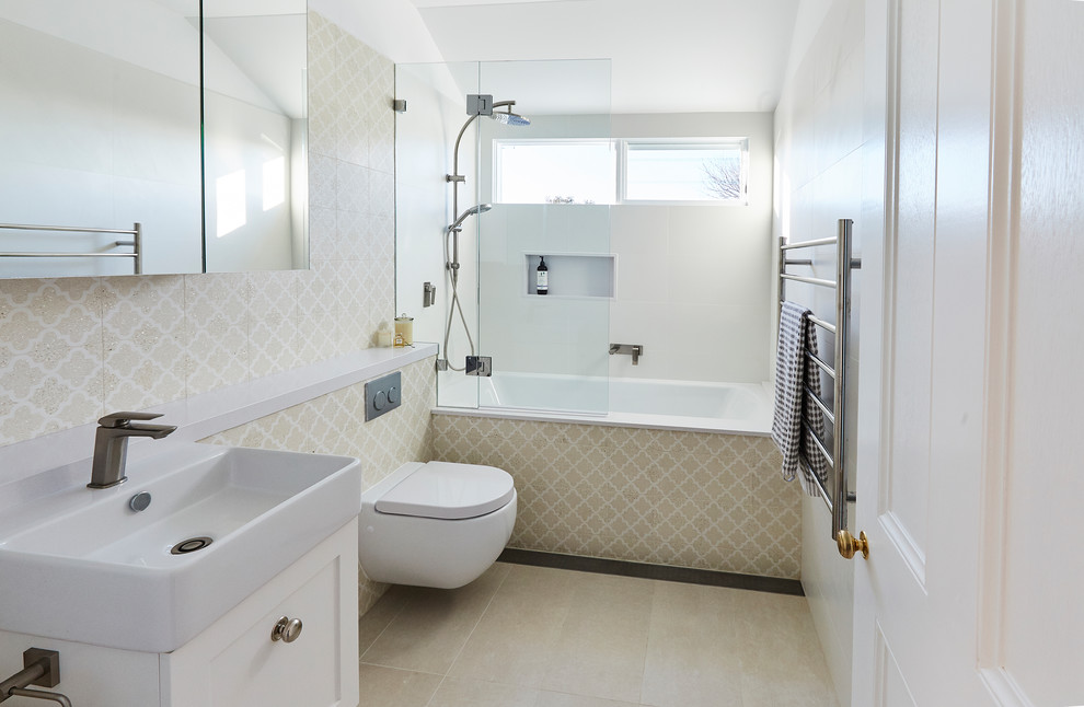 Mid-sized transitional kids bathroom in Sydney with shaker cabinets, white cabinets, an alcove tub, an open shower, a wall-mount toilet, beige tile, ceramic tile, beige walls, ceramic floors, a wall-mount sink, solid surface benchtops, beige floor, an open shower and white benchtops.