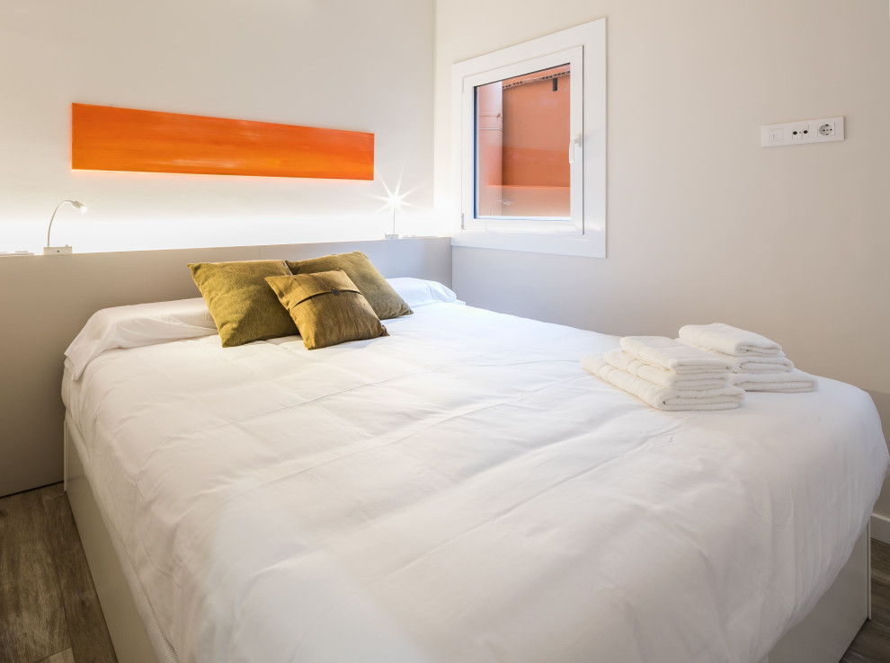Immagine di una camera matrimoniale minimalista di medie dimensioni con pareti beige, pavimento in legno massello medio e pavimento marrone