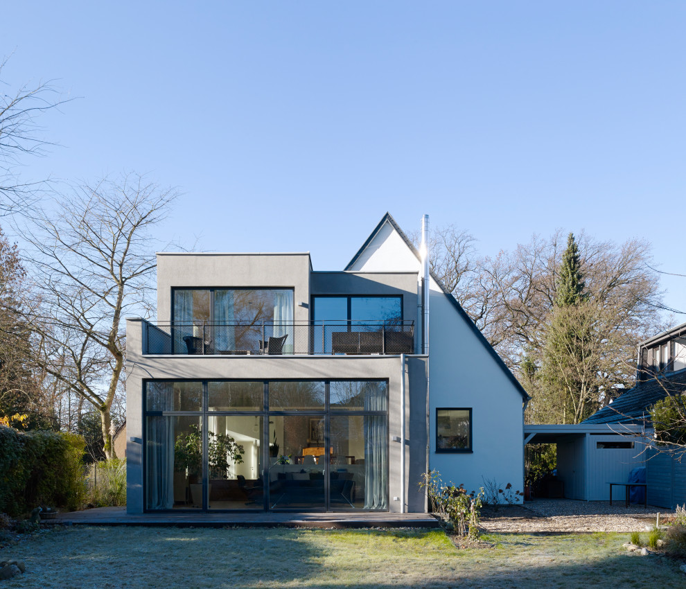 Design ideas for a contemporary stucco grey house exterior in Cologne with a flat roof and a mixed roof.