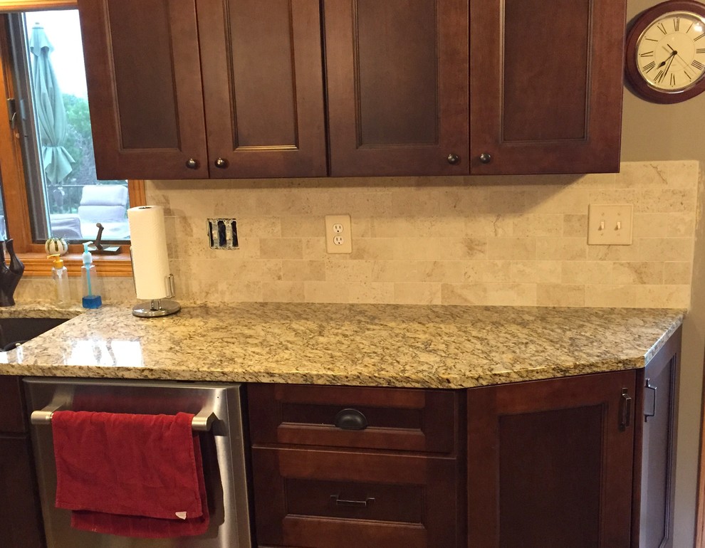 Inspiration for a mid-sized timeless kitchen remodel with an undermount sink, recessed-panel cabinets, dark wood cabinets, granite countertops, beige backsplash, porcelain backsplash, stainless steel appliances and multicolored countertops