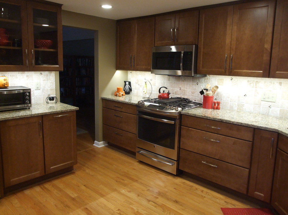 Eat-in kitchen - mid-sized transitional l-shaped light wood floor eat-in kitchen idea with a double-bowl sink, flat-panel cabinets, medium tone wood cabinets, granite countertops, cement tile backsplash, stainless steel appliances and no island