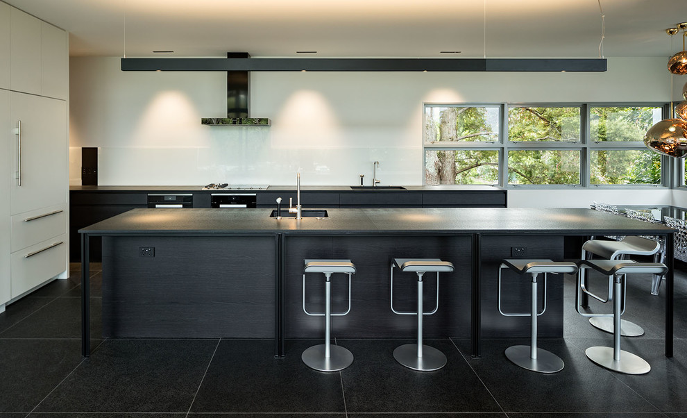Design ideas for a modern eat-in kitchen in Auckland with black cabinets, white splashback, glass sheet splashback, with island, black floor, black benchtop and ceramic floors.