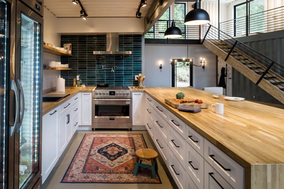Exempel på ett industriellt kök, med träbänkskiva, blått stänkskydd, stänkskydd i keramik, rostfria vitvaror, betonggolv och grått golv