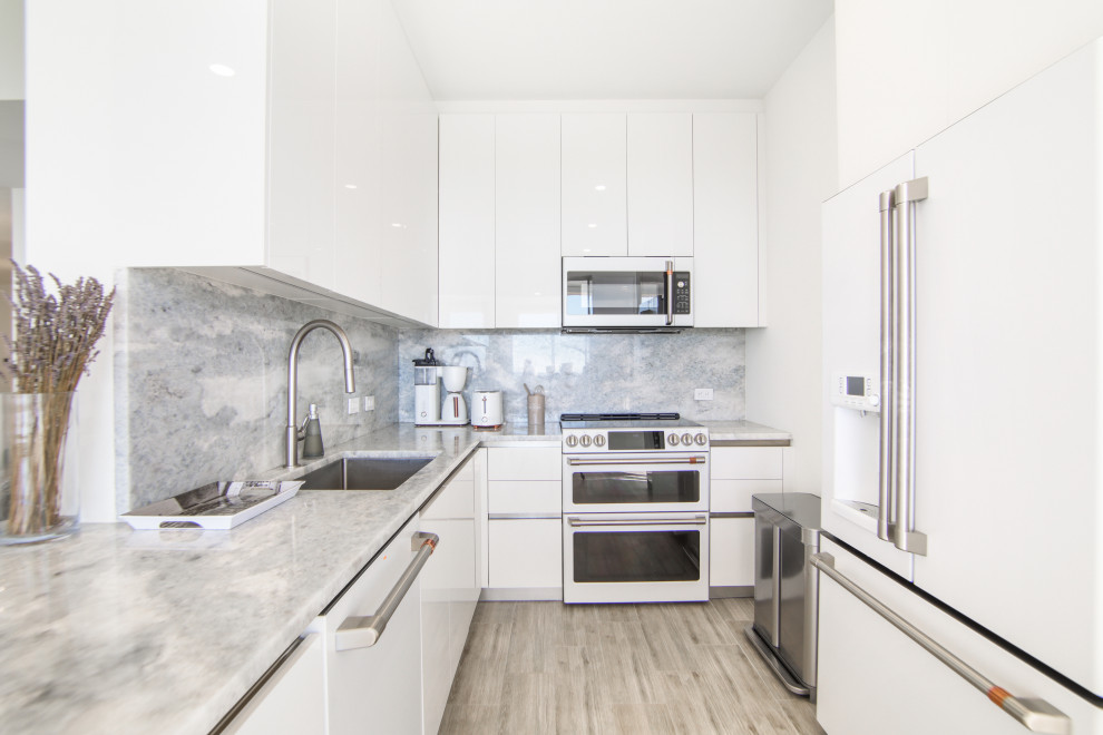 Eat-in kitchen - mid-sized u-shaped porcelain tile and brown floor eat-in kitchen idea in Miami with an undermount sink, flat-panel cabinets, white cabinets, quartzite countertops, gray backsplash, quartz backsplash, white appliances, two islands and gray countertops
