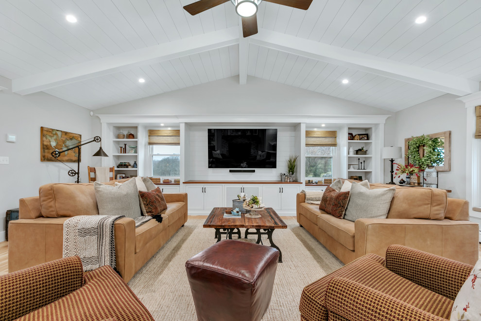 Example of a mid-sized transitional enclosed brown floor, medium tone wood floor and vaulted ceiling living room design in New York with a media wall and gray walls