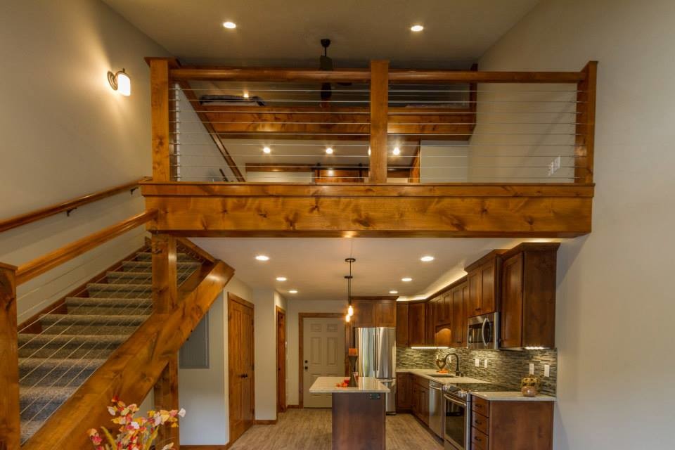 Inspiration for a mid-sized country l-shaped eat-in kitchen in Seattle with a single-bowl sink, raised-panel cabinets, dark wood cabinets, soapstone benchtops, beige splashback, stone slab splashback, stainless steel appliances, light hardwood floors and with island.
