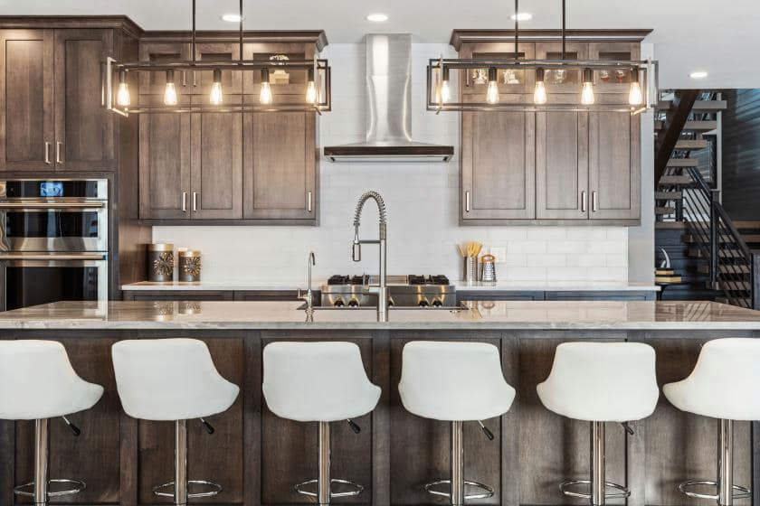 Large minimalist l-shaped light wood floor and beige floor open concept kitchen photo with a farmhouse sink, shaker cabinets, dark wood cabinets, quartzite countertops, white backsplash, subway tile backsplash, stainless steel appliances, an island and multicolored countertops