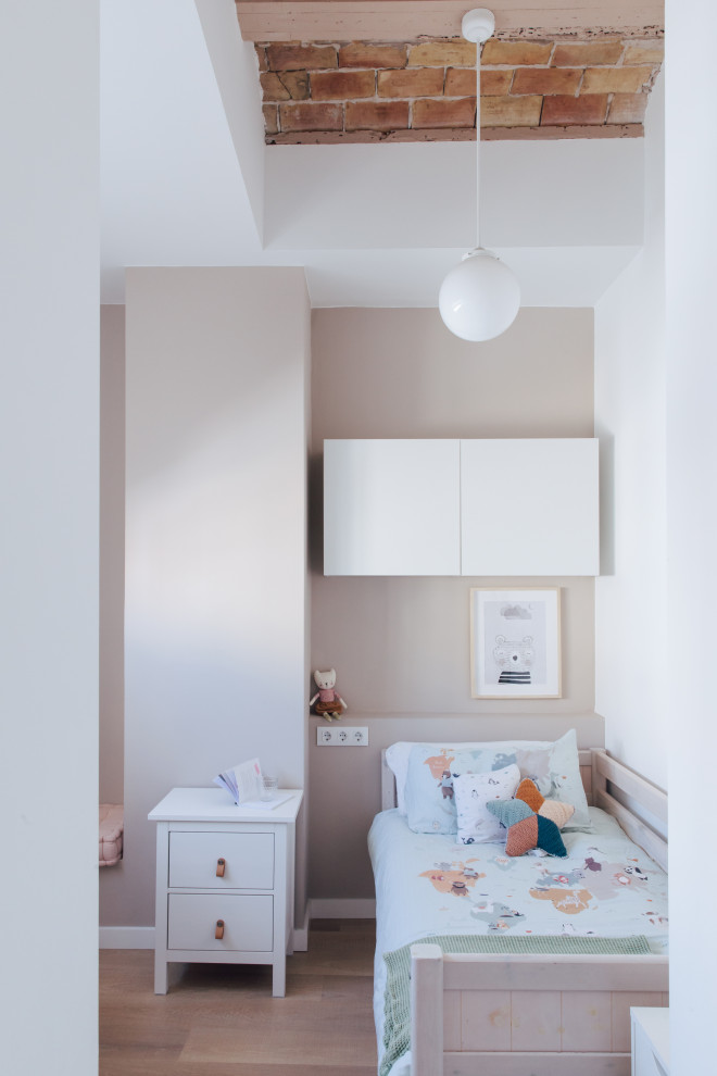 This is an example of a small industrial kids' bedroom for kids 4-10 years old and girls in Valencia with beige walls, laminate floors and vaulted.