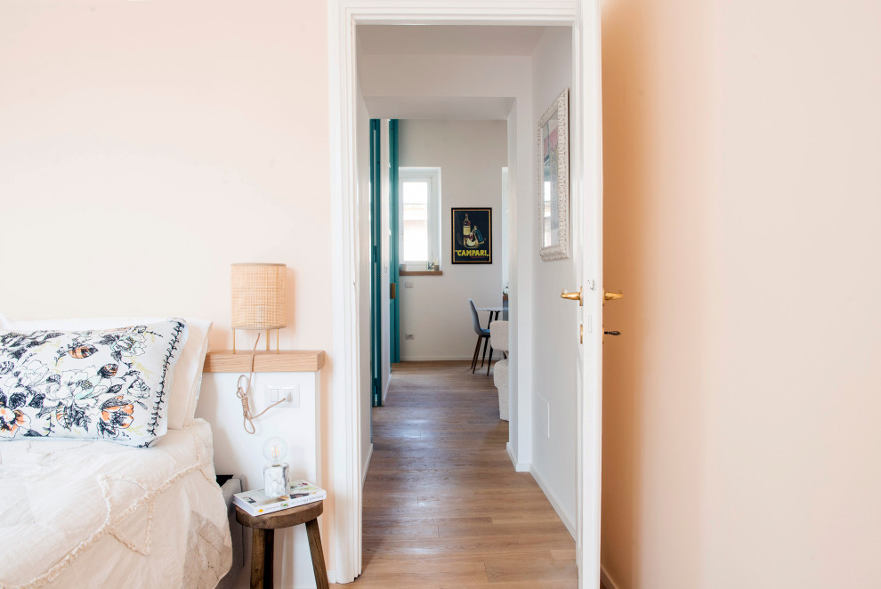 Foto de dormitorio principal escandinavo de tamaño medio sin chimenea con paredes rosas, suelo de madera clara y suelo marrón