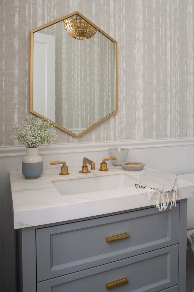 Inspiration for a small transitional powder room in Los Angeles with grey cabinets, a two-piece toilet, beige walls, an undermount sink, marble benchtops, recessed-panel cabinets and white benchtops.