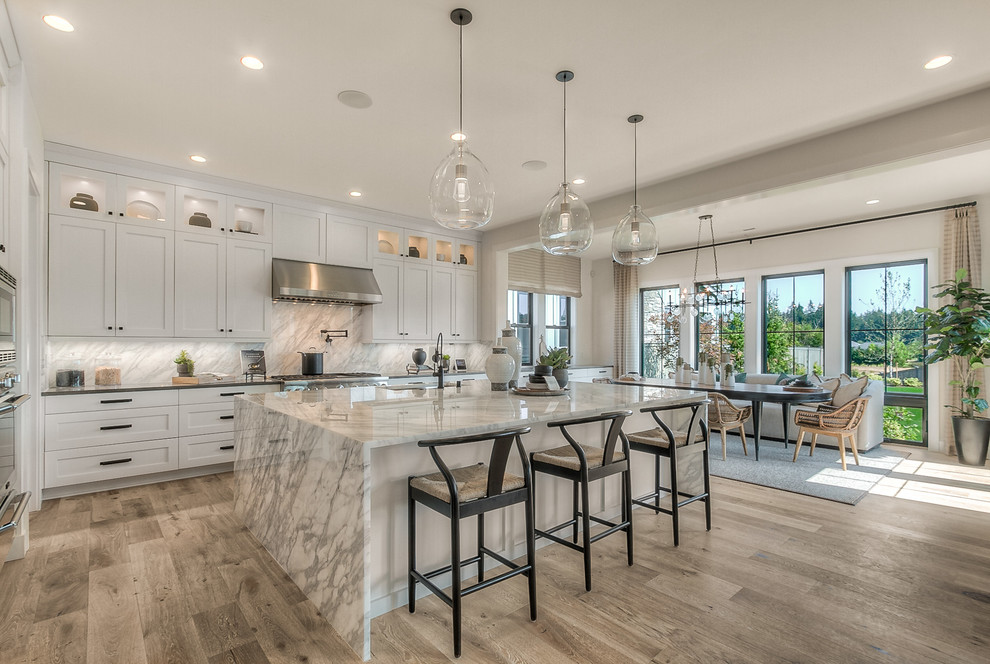 Inspiration for an expansive transitional eat-in kitchen in Seattle with an undermount sink, white cabinets, stainless steel appliances, light hardwood floors, with island, grey benchtop, shaker cabinets, multi-coloured splashback and stone slab splashback.